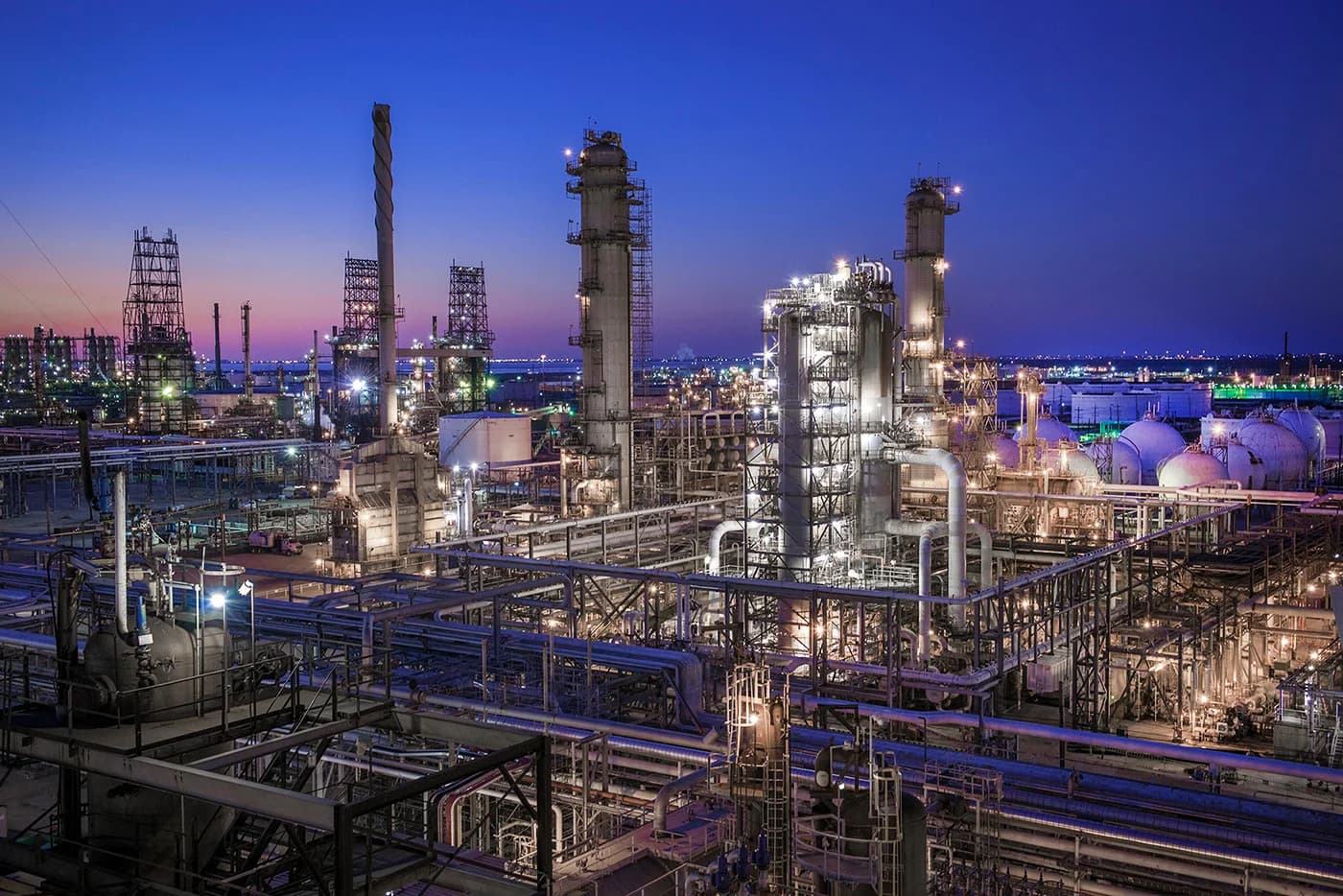 Refinery process towers and storage spheres illuminated at dusk